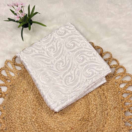 White patterned napkin on a textured surface with a plant in the corner