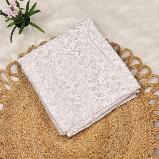 Folded white jacquard silk blend saree by RAE Trends with a self-design floral woven pattern, displayed on a neutral background.
