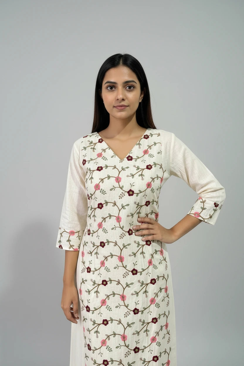 Woman wearing a white floral dress against a plain background