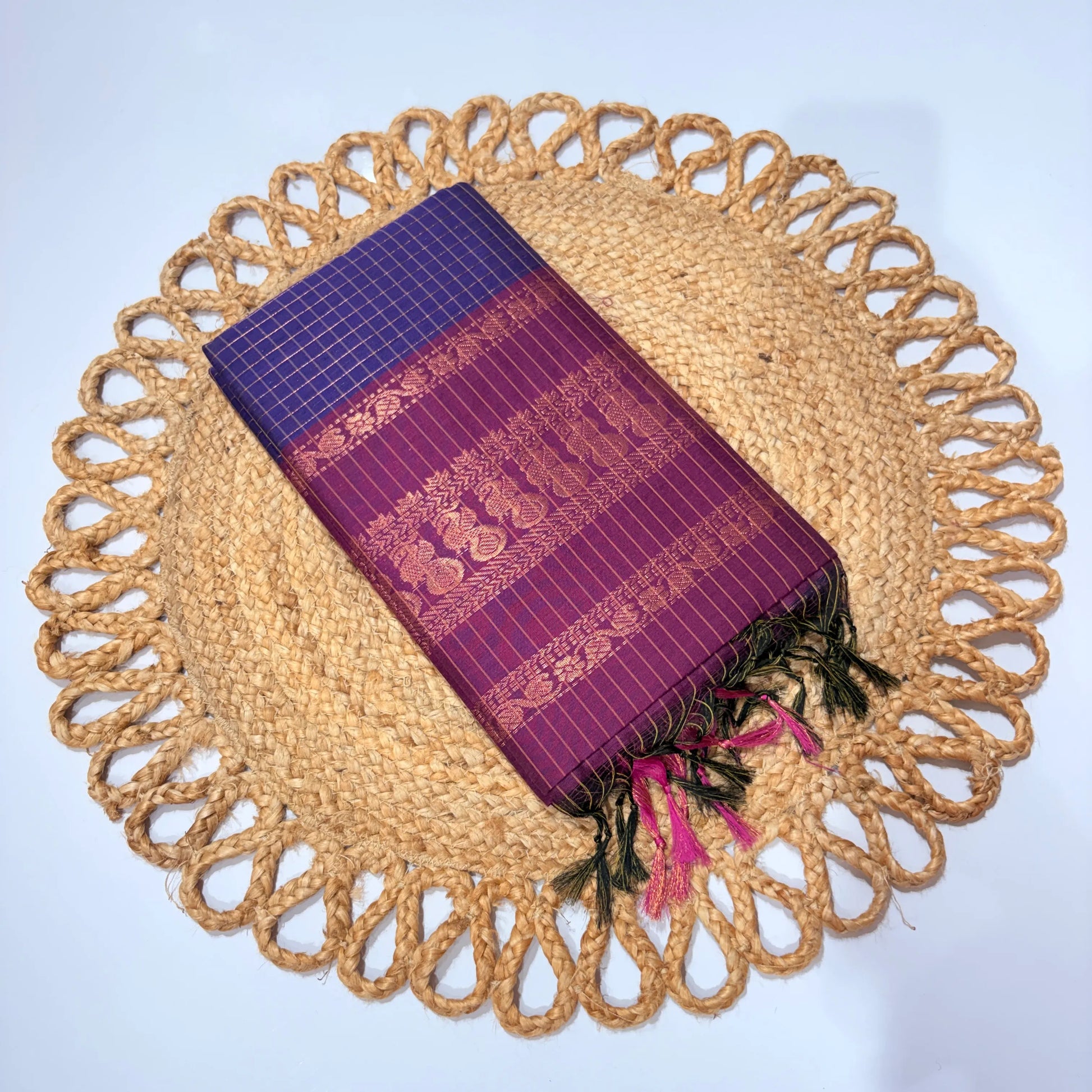 Purple woven fabric with gold patterns on a round woven placemat