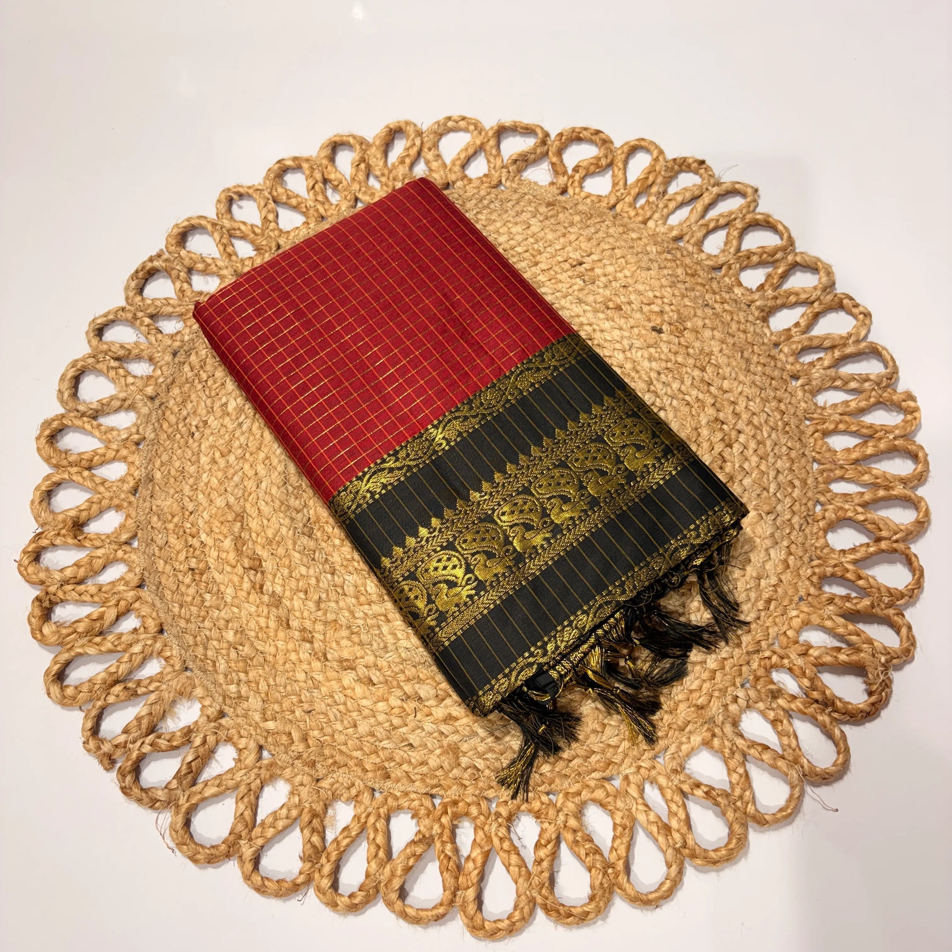 Red and black patterned fabric with gold embroidery on a woven placemat.