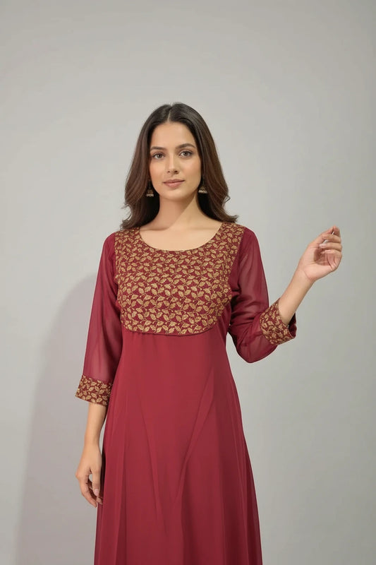 Woman wearing a maroon dress with gold patterns against a neutral background